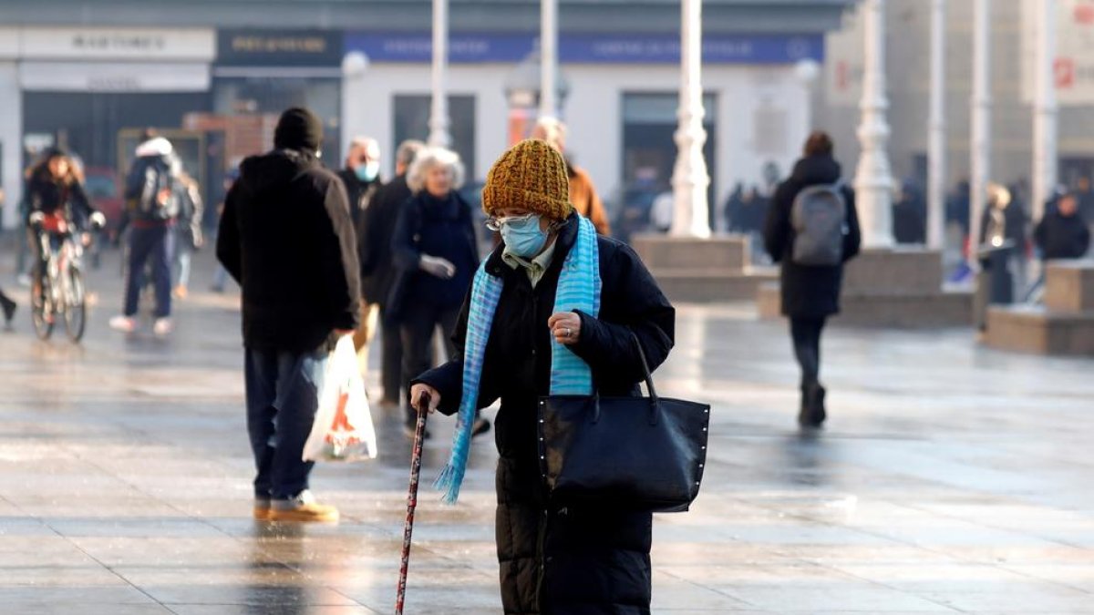 Una mujer andando con mascarilla.