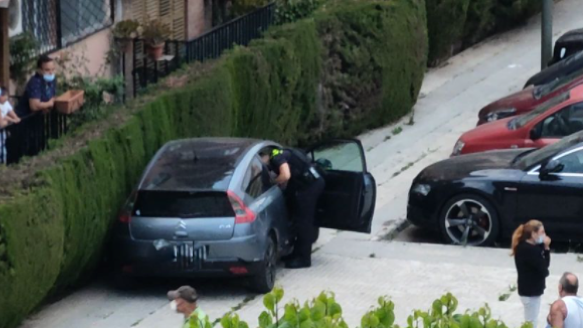 Uno de los agentes inspeccionando el vehículo abandonado a la acera.