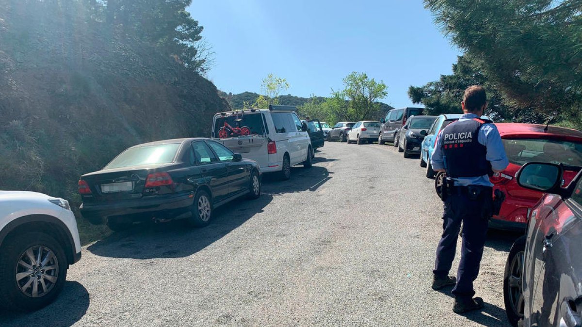 Un mosso davant fileres de cotxes mal aparcats en vorals de la carretera durant les vacances de Setmana Santa a Tarragona.
