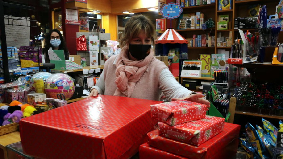 La presidenta presidenta de la Unió de Botiguers, Meritxell Barberà, entregant a una clienta regals embolicats, en el primer dissabte de la campanya de Nadal