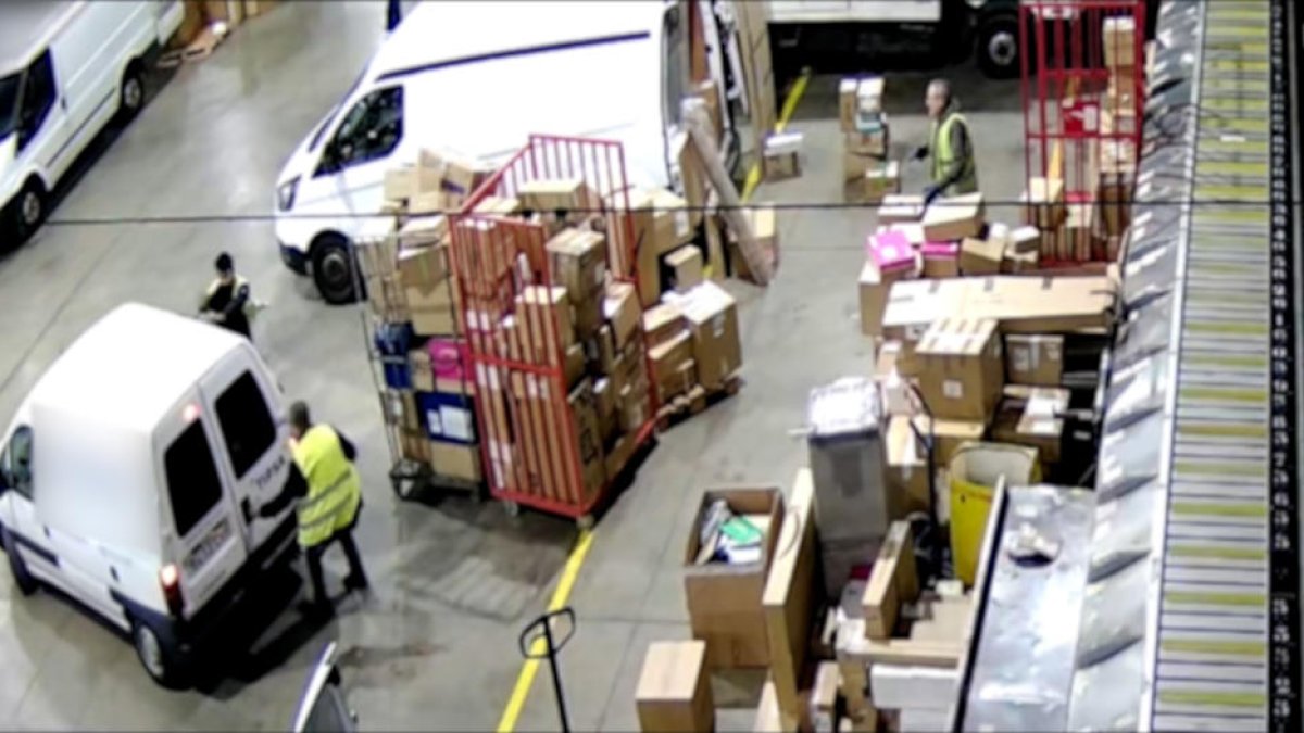 Dos homes detinguts pels Mossos en una empresa de missatgeria obrint una furgoneta per carregar paquets.
