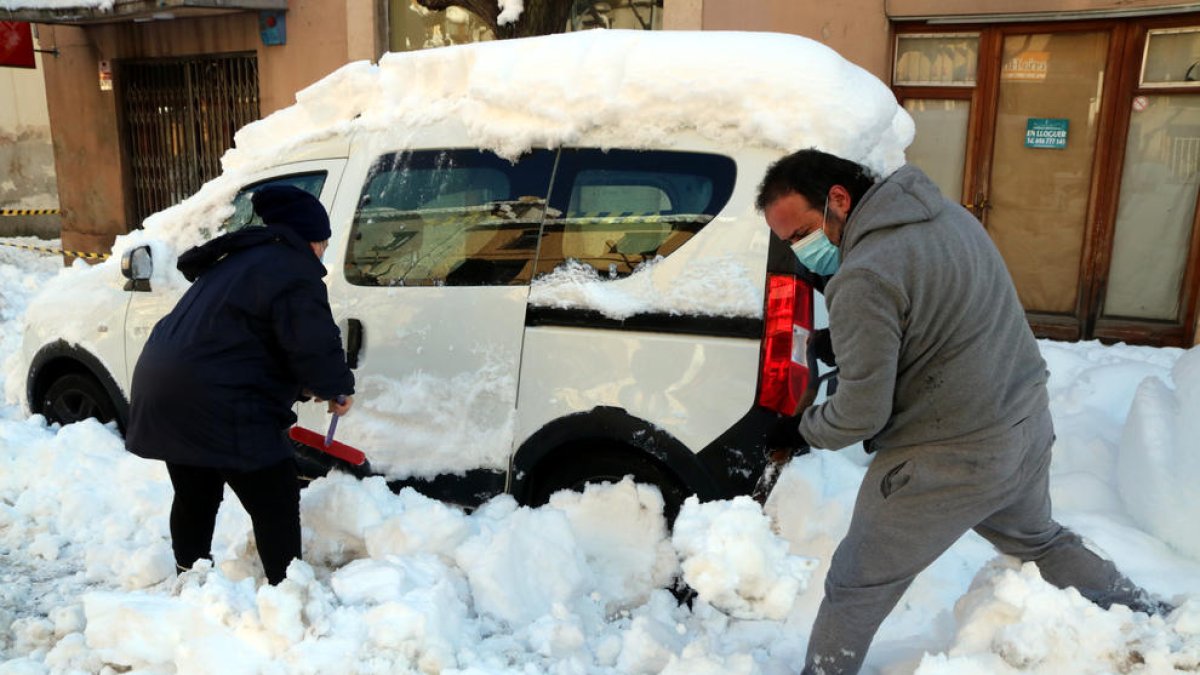 Dos veïns de Falset desenterrant el seu vehicle, colgat per la neu.