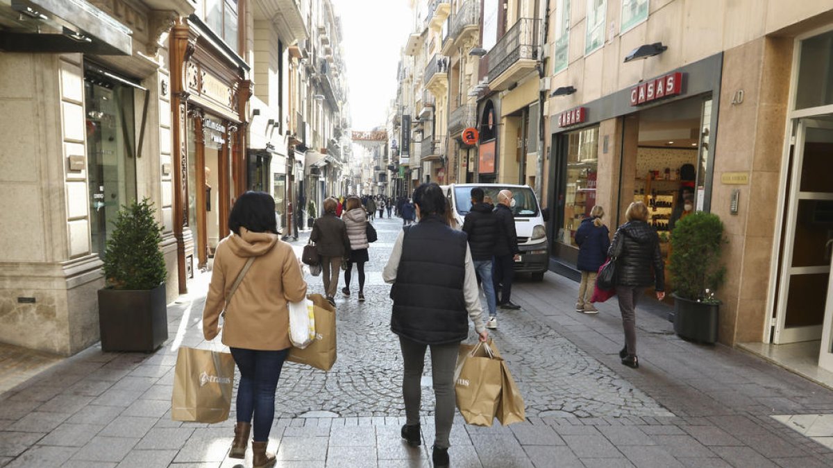 Ciudadanos con bolsas por el carrer de Monterols.
