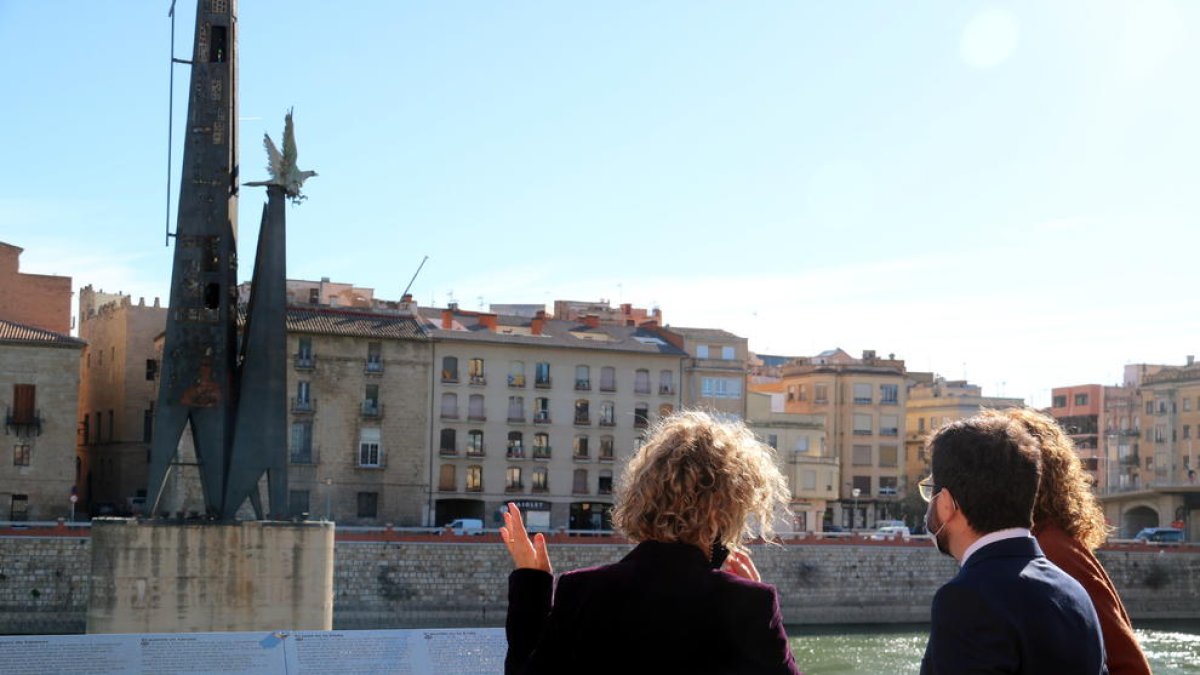 El vicepresident Pere Aragonès, la consellera de Justícia Ester Capella i l'alcaldessa de Tortosa Meritxell Roigé, d'esquenes, mirant el monument franquista des del passeig de l'Ebre.