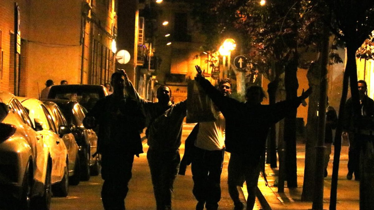 La silueta de varios jóvenes en la calle que celebran el final del toque de queda a Gracia