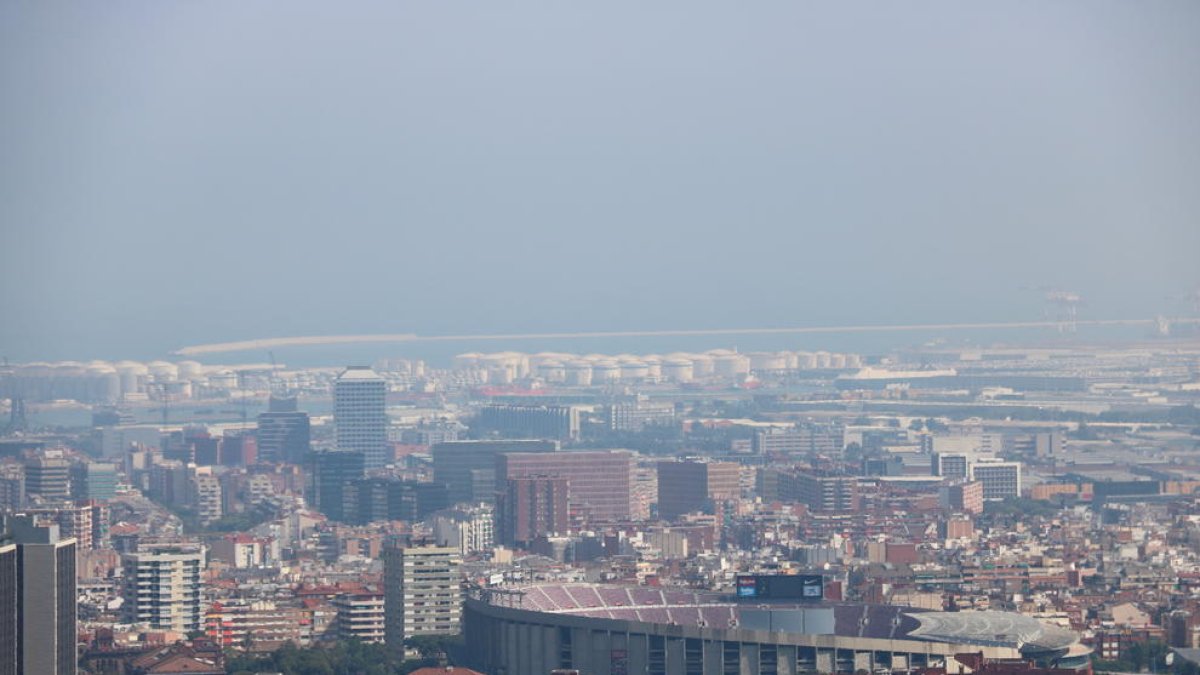 Barcelona con el Camp Nou en primero plano y el puerto de fondo en niebla por polución en el fondo.