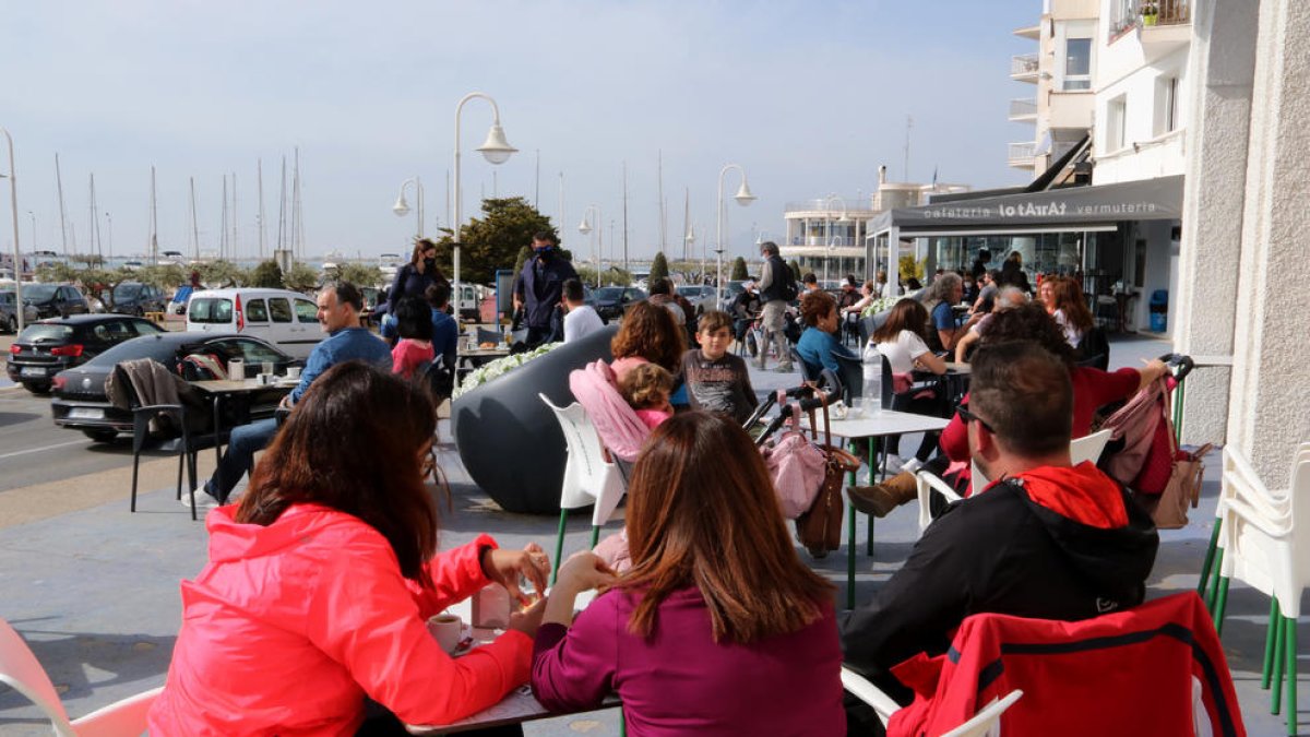 Personas consumiendo en una terraza de un bar de la zona marítima de l'Ampolla esta Semana Santa.