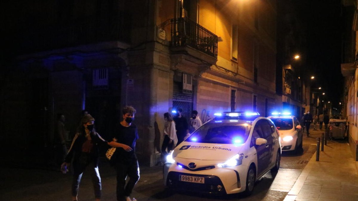 Dos cotxes de la Guàrdia Urbana patrullant pel carrer.