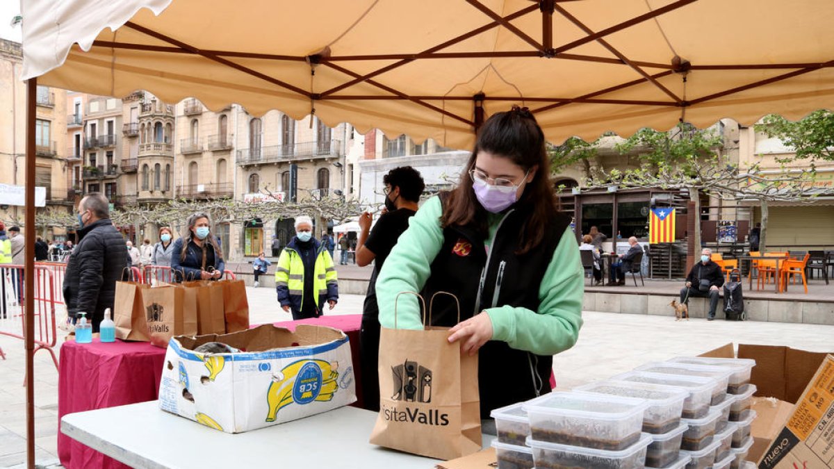 Una noia preparant racions de faves a la plaça del Pati de Valls, un dels punts habilitats de recollida de la 3a edició de la Favatada.