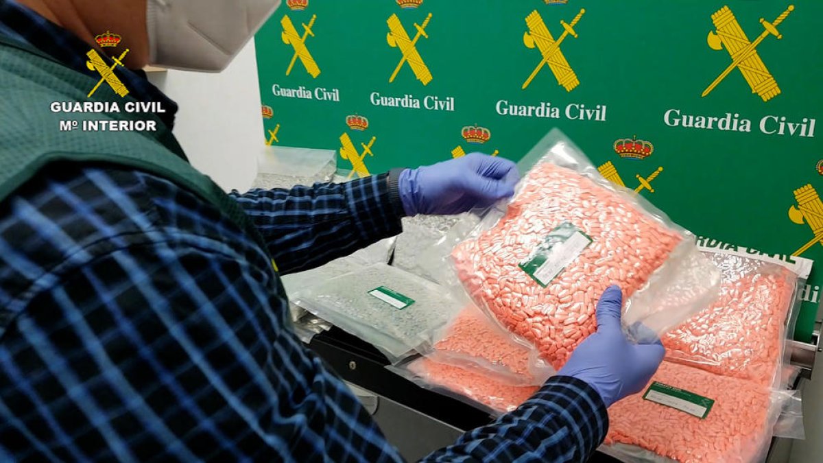 Imagen policial de un agente de la Guardia Civil interviniendo varios paquetes con pastillas de MDMA encontrados entre el equipaje de un conductor.