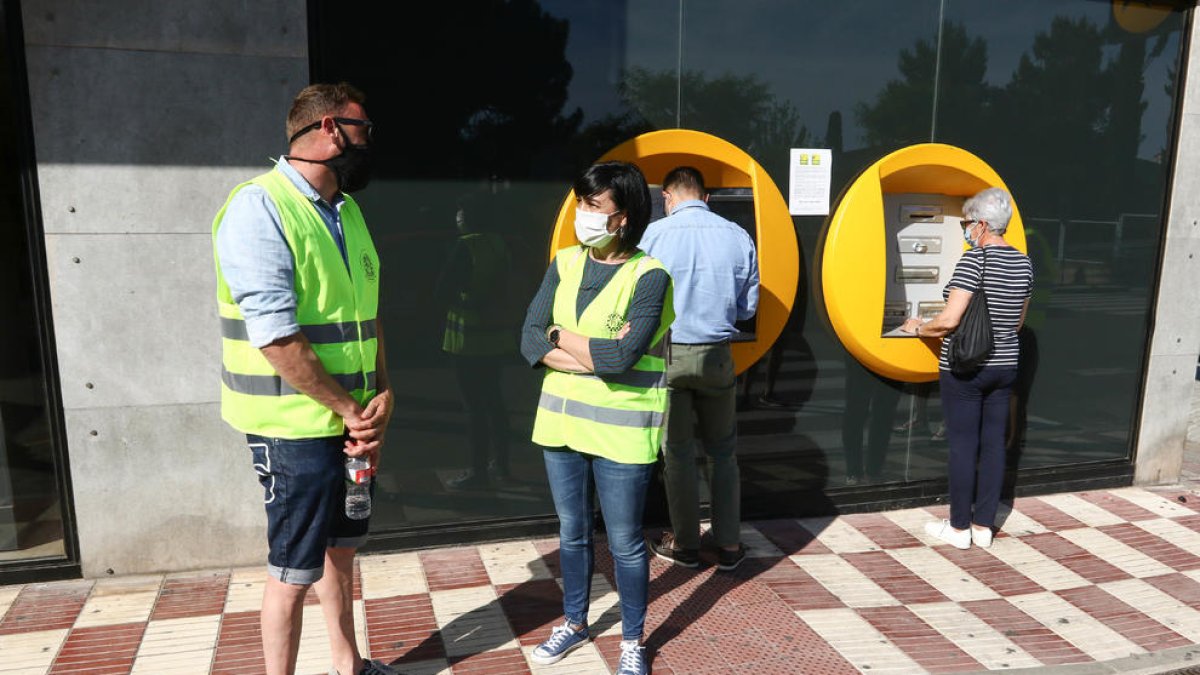 Imagen de Trinitat con una voluntaria en el cajero automático de la Caja a Sant Pere i Sant Pau.