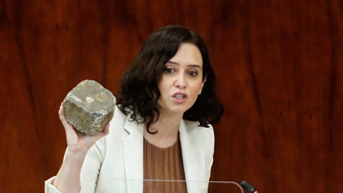 La presidenta de la Comunidad de Madrid, Isabel Díaz Ayuso, muestra a la Asamblea de Madrid un adoquín supuestamente utilizado a los disturbios