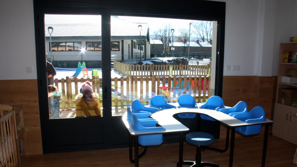 Un aula de un jardín de infancia y donde se ven alumnos del centro en el patio.