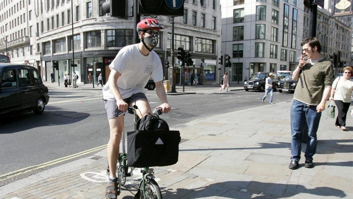 Un londinense se dirige a trabajar en bicicleta con mascarilla en la cara en Londres, Reino Unido.