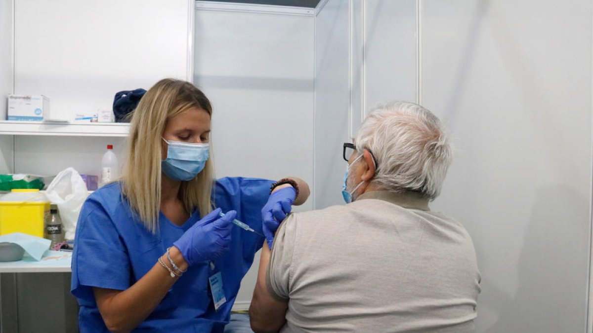 Una enfermera vacuna un hombre en uno de los box del punto de vacunación masiva habilidad en Fira de Barcelona.