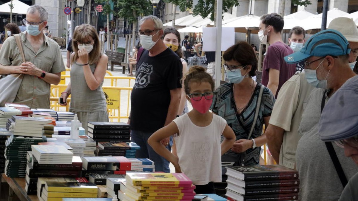 Compradors amb mascaretes mirant llibres al Sant Jordi d'estiu de Girona.