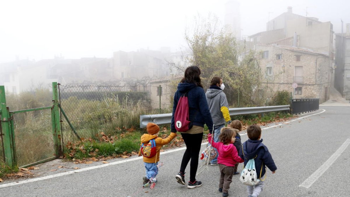 L'educadora i els infants de l'espai familiar d'autogestionat de La Muntanya d'Arbolí caminat pel poble d'esquenes.