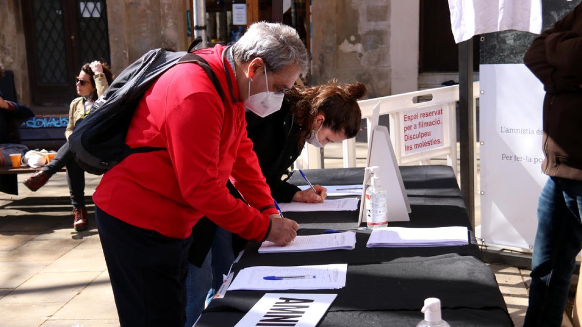 Dos personas firman a favor de la ley de amnistía, en un acto de Òmnium en Barcelona