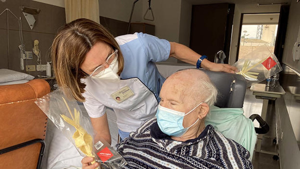 Un anciano de un geriátrico recibiendo una palma, en el marco de una campaña solidaria de un taller artesano de la Vilella Baixa.