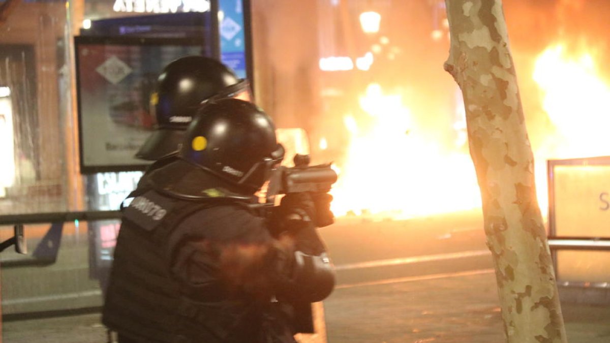 Un agent dels Mossos d'Esquadra dispara una bala de foam en el marc dels aldarulls per l'empresonament del cantant Pablo Hasel a Barcelona.