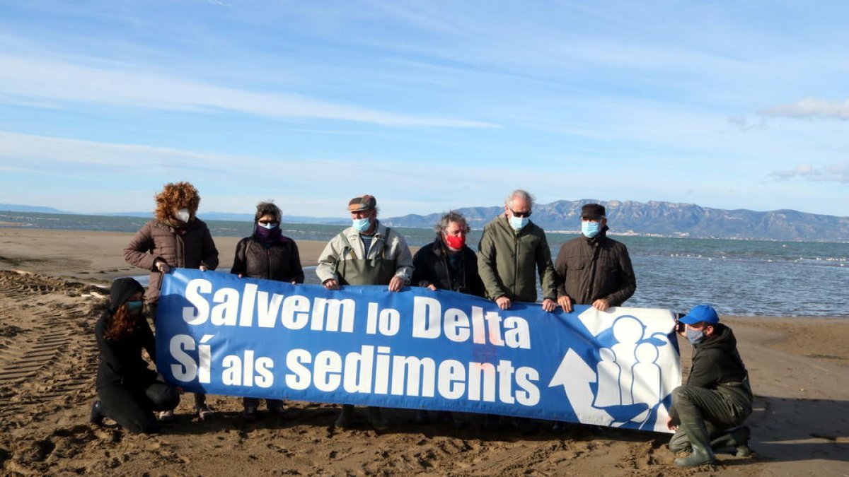 Activistes de l'Associació Sediments amb una pancarta reivindicativa abans de començar l'acció visual per denunciar la fragilitat de la barra del Trabucador.