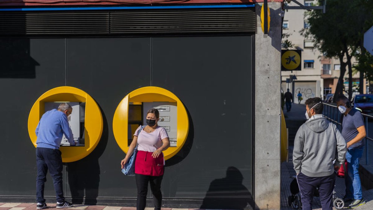 Imagen de algunos vecinos de Sant Pere i Sant Pau retirando dinero de uno de los cajeros del barrio.