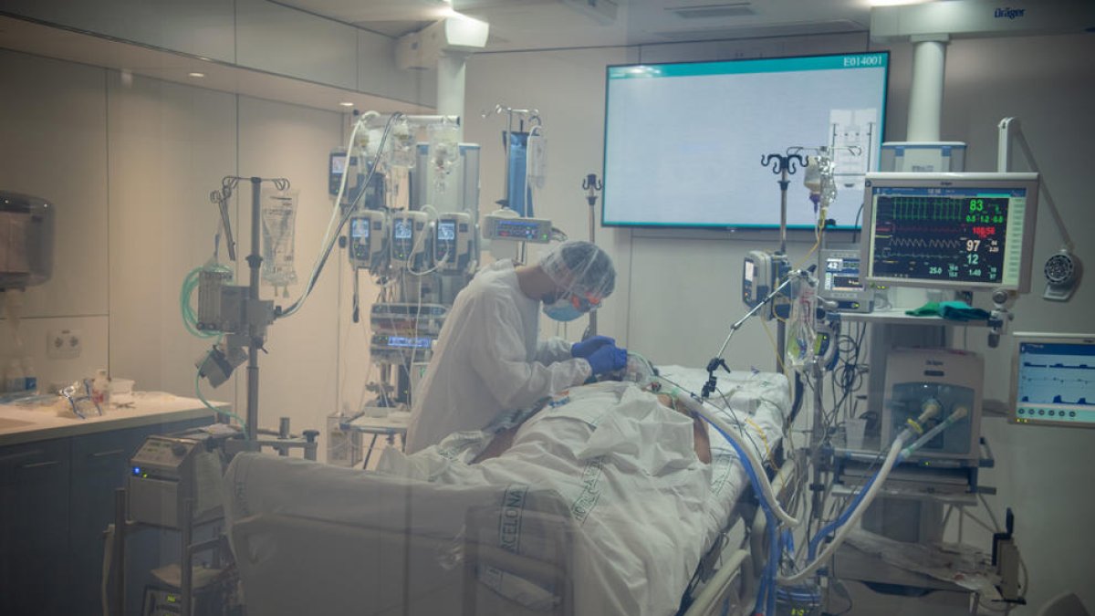 Un metge atenent amb un pacient amb covid-19 a l'Àrea de Vigilància Intensiva (AVI) de l'Hospital Clínic de Barcelona.