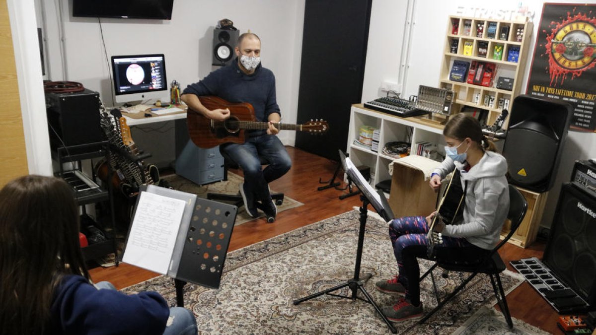 Albert Gilabert, professor de guitarra de l'aula El Traster de Mollerussa, fent classe amb dos alumnes, en la represa de les activitats extraescolars.