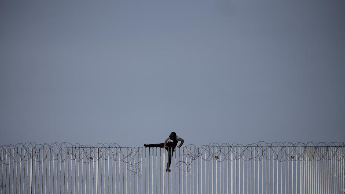 Un menor immigrant no acompanyat intenta saltar una tanca, a Ceuta.