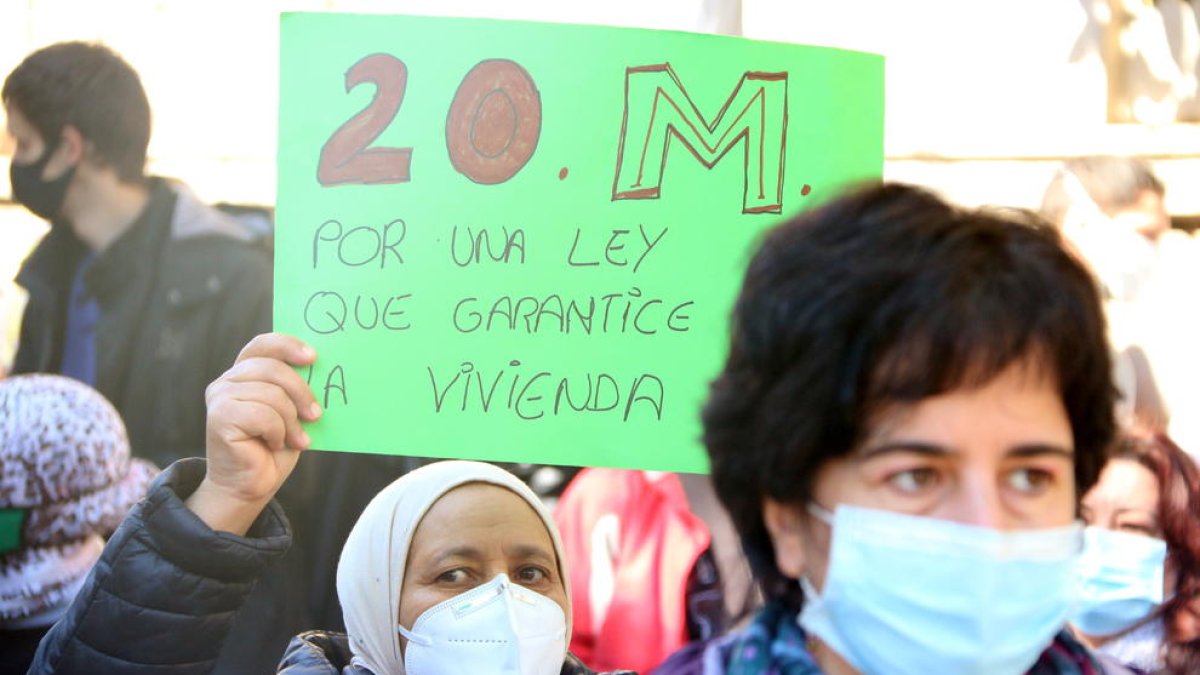 Una dona aixeca una pancarta a la manifestació del moviment per l'habitatge.