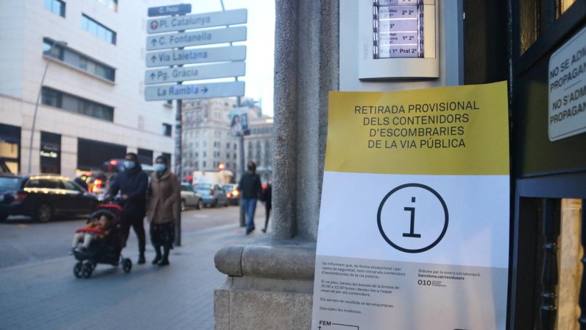 Un cartel a la puerta de un bloque de pisos de Barcelona avisa que se han retirado los contenedores de la calle por precaución.