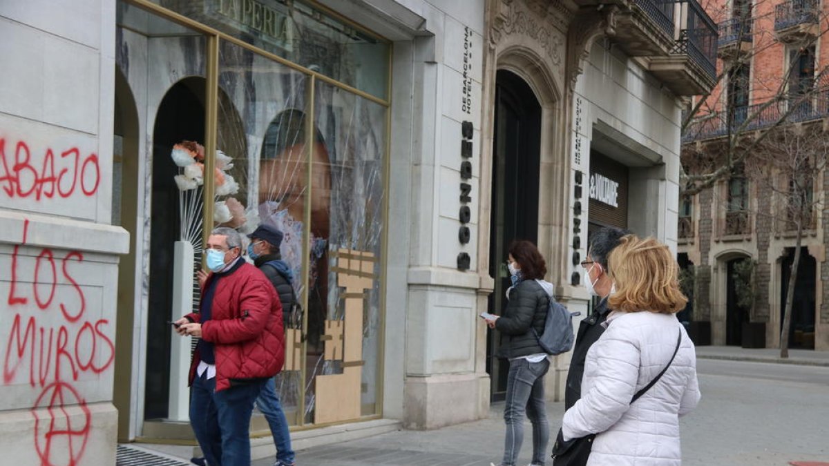 Vianants curiosos miren les destrosses causades a les botigues del Passeig de Gràcia.