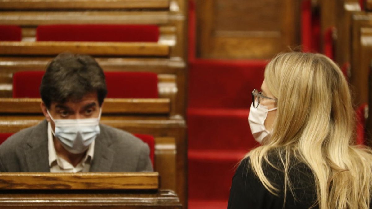 El líder de ERC en el Parlament, Sergi Sabrià, sentado en su escaño del Parlament mientras la diputada y concejala de JxCat Elsa Artadi sube las escaleras del hemiciclo.