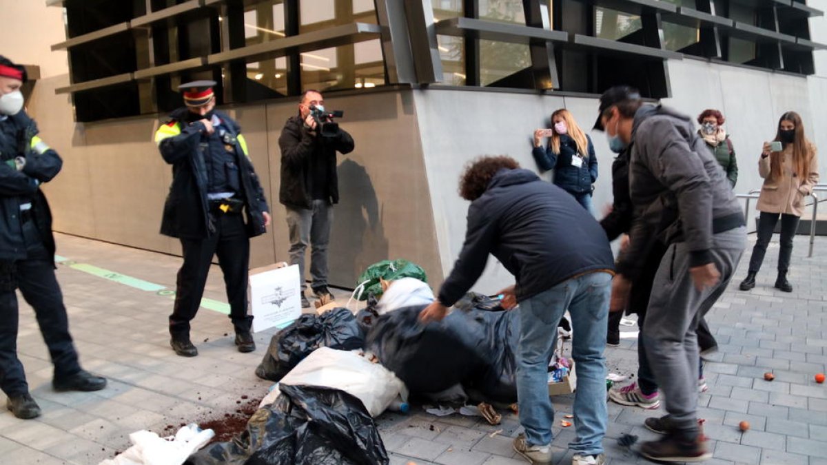 Alguns restauradors llençant bosses de brossa davant del cordó policial a les portes de la seu del Govern.