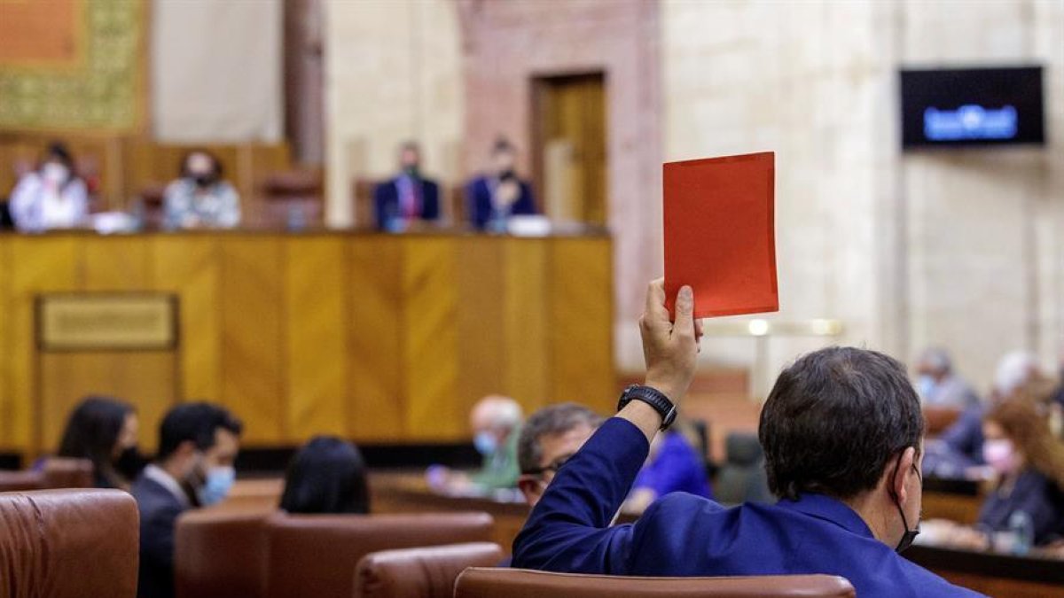 Un diputado de Vox indica el sentido negativo de su voto a una votación al parlamento andaluz.