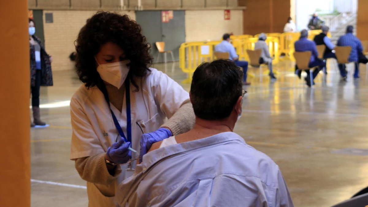 Una infermera vacuna un home de 65 anys el dia en què es reprèn la vacunació de la covid-19 amb AstraZeneca.