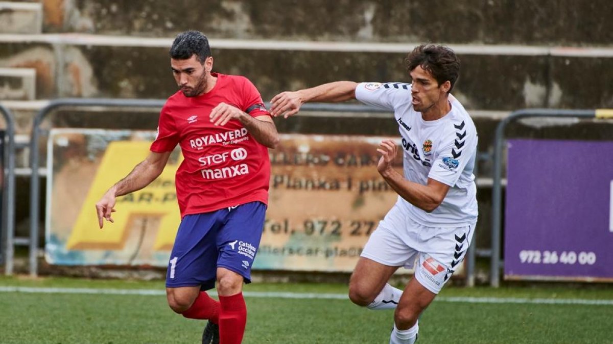 Un jugador del Olot con el esférico perseguido por un jugador del Nàstic.