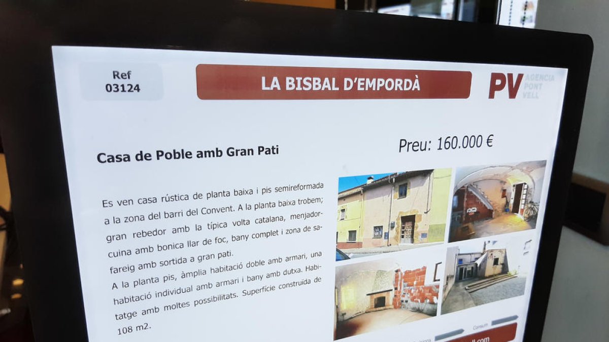 Un cartel de una casa en venta en una inmobiliaria de la Bisbal d'Empordà.