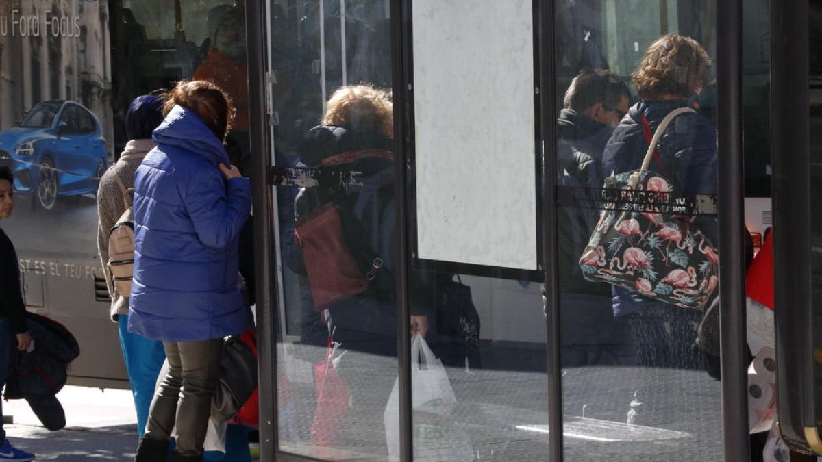 Imatge d'arxiu de gent protegint-se del vent a una parada d'autobús.