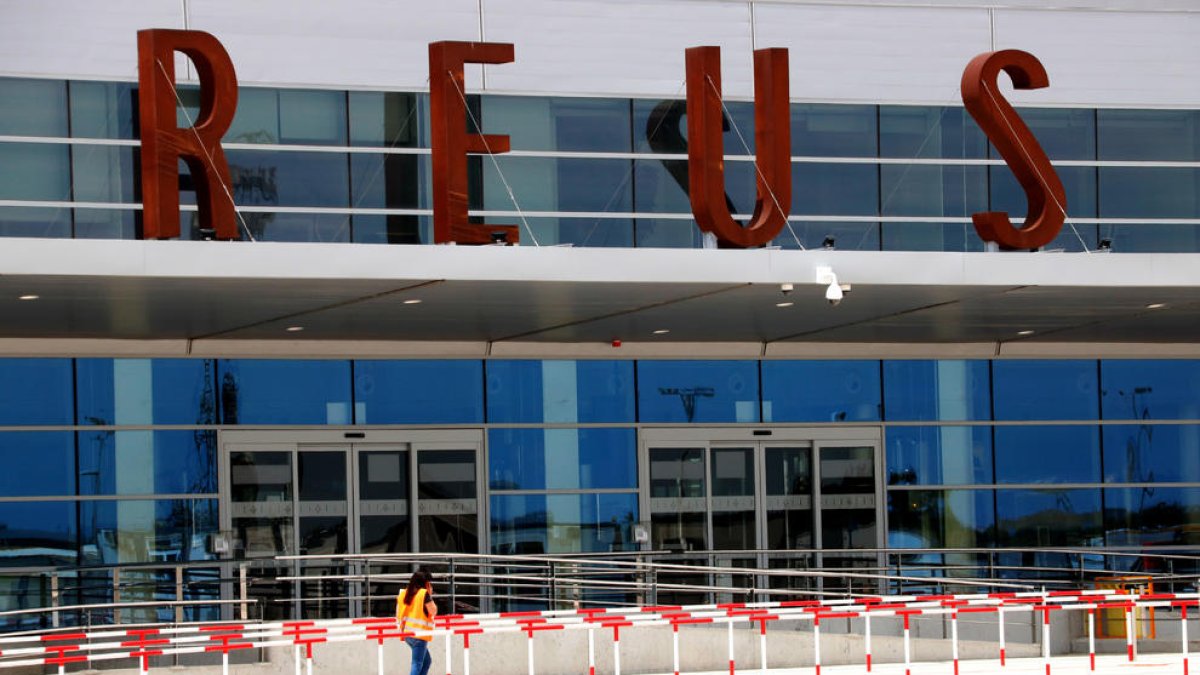 Una operària que passa per davant la nova terminal de l'Aeroport de Reus.
