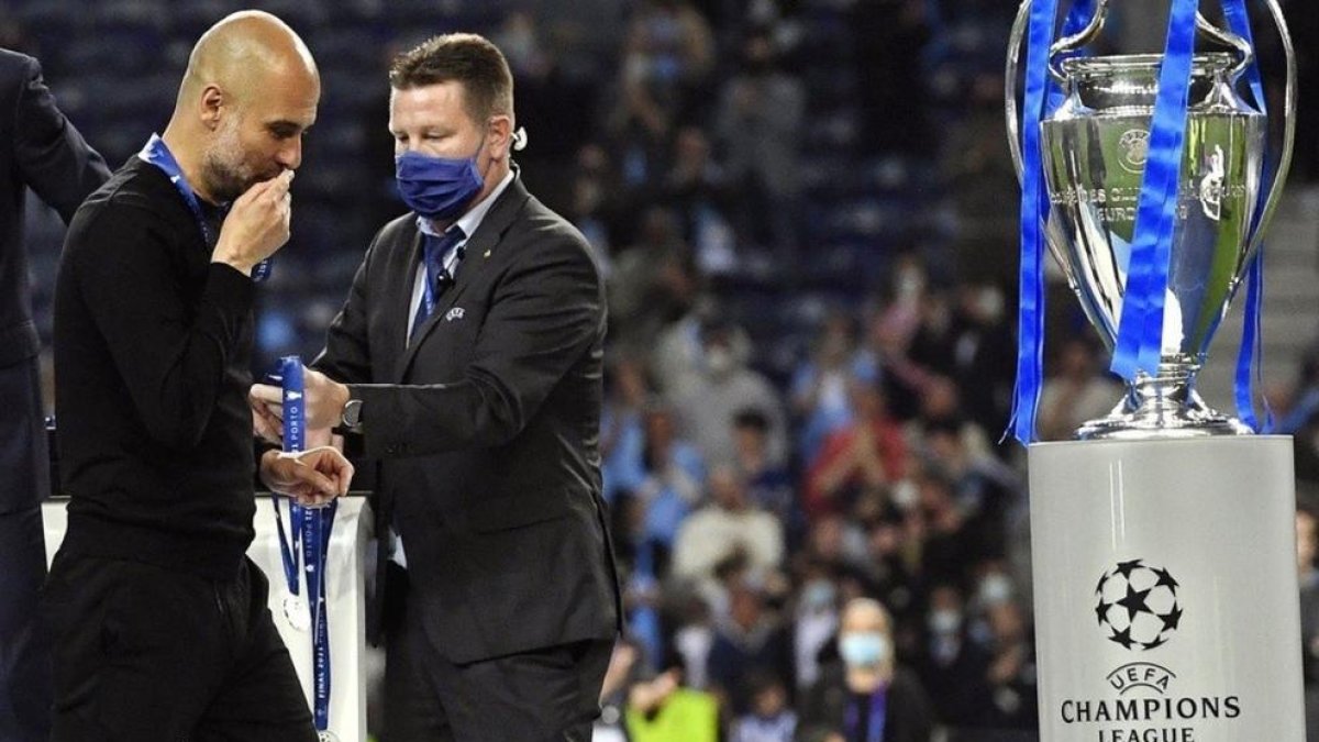 Pep Guardiola dando un beso en la medalla que lo acreditaba como segundo a la Champions.