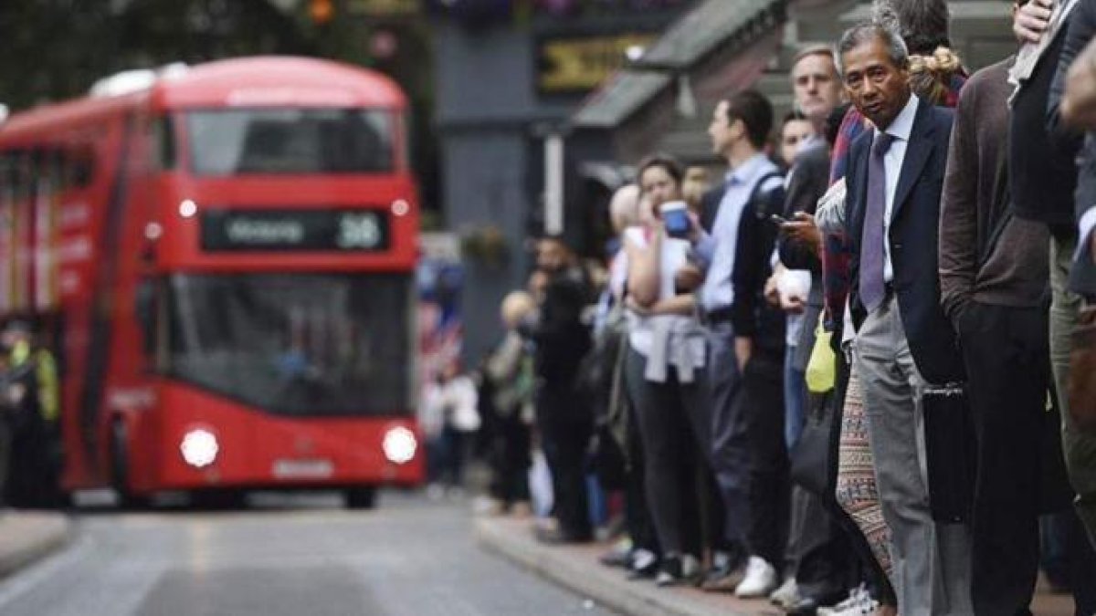 Treballadors esperen en una parada d'autobús de Londres.