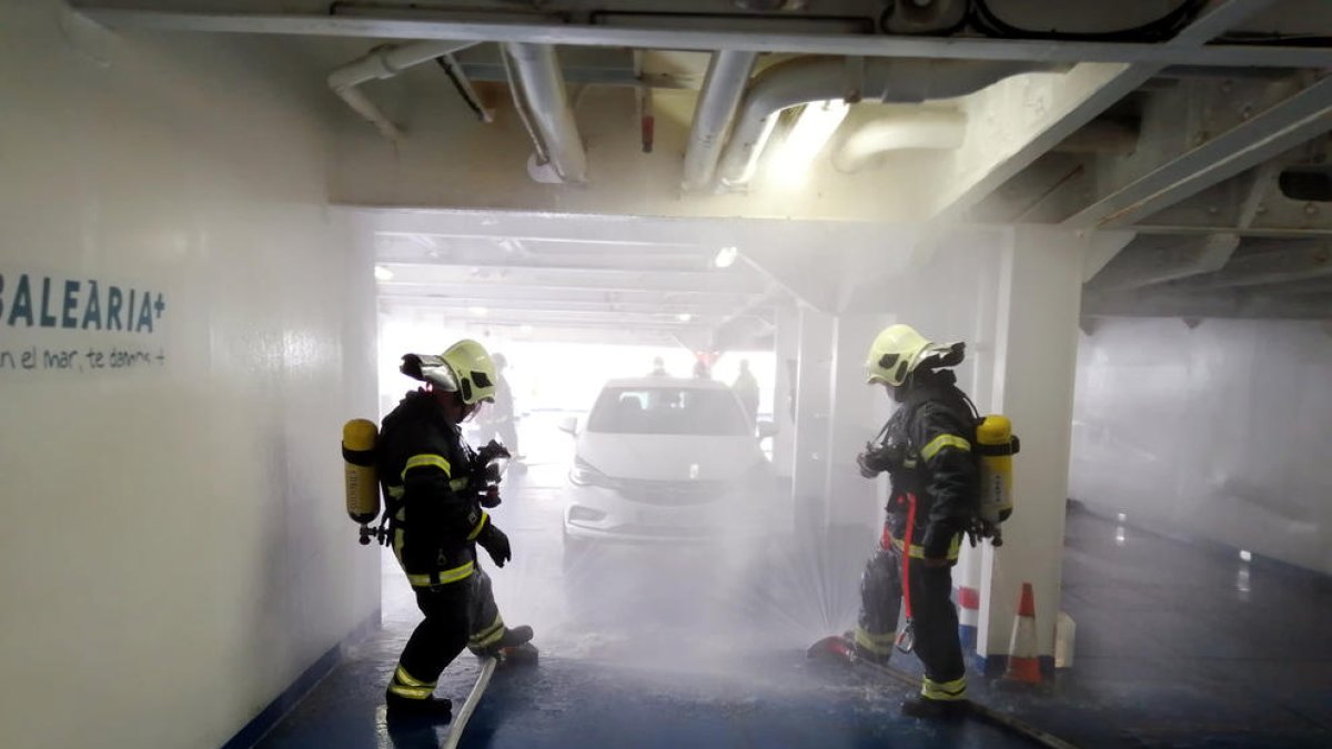 Los Bomberos sofocando el simulacro de incendio del coche eléctrico en el ferri de Baleària