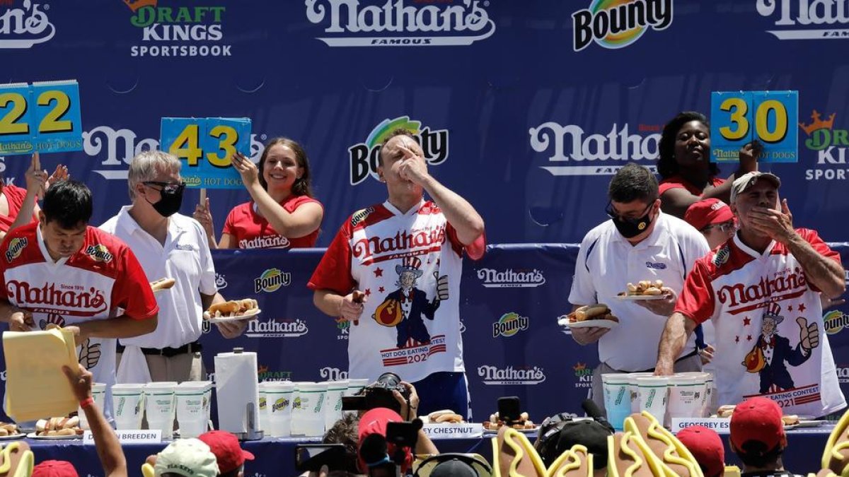 Joey Chestnut en el centro de la imagen compitiendo con dos rivales más.