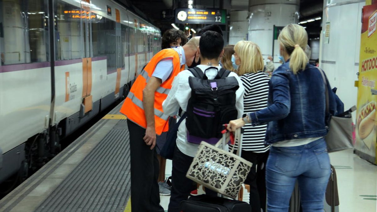 Personal de l'estació de Barcelona-Sants a l'andana informant als afectats per la vaga dels maquinistes.