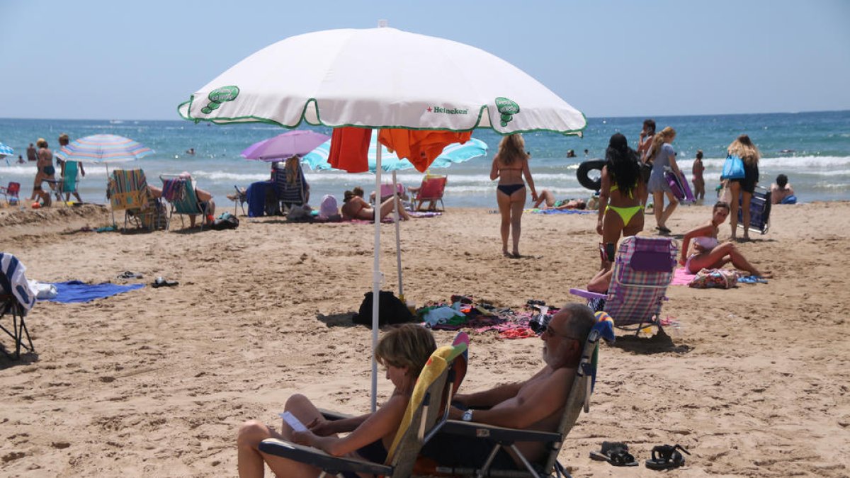 Plano medio de dos personas bajo un parasol en la playa de Salou.