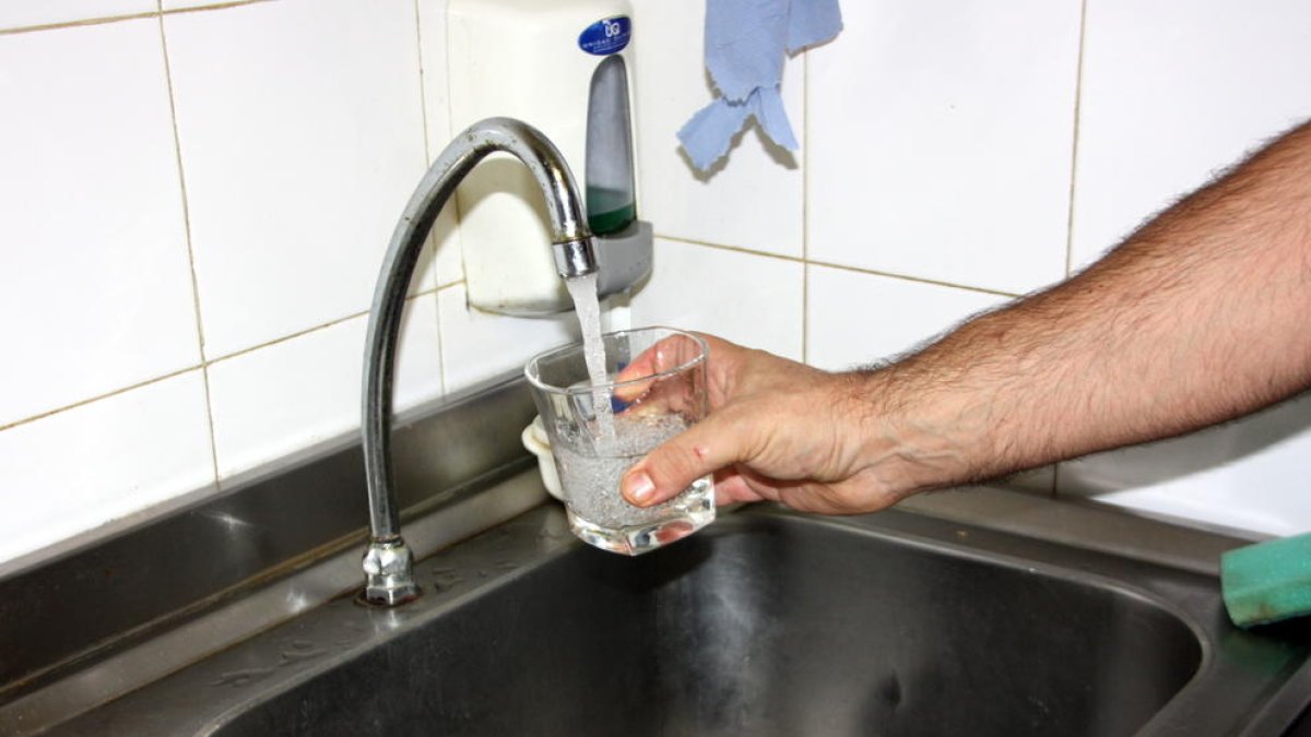 Imagen de archivo de una mano llenando un vaso de agua al grifo.