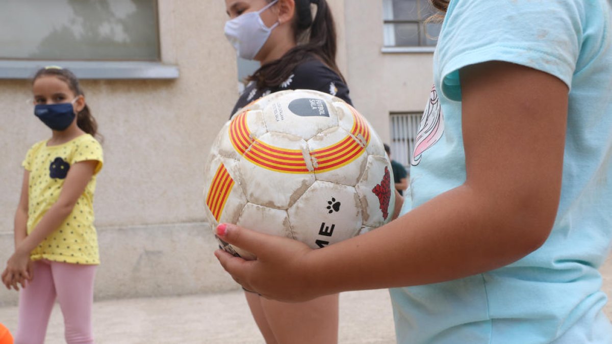 Plano detalle de una pelota a manos de una niña participando en el centro de verano de la Fundació Pere Tarrés en Torredembarra.