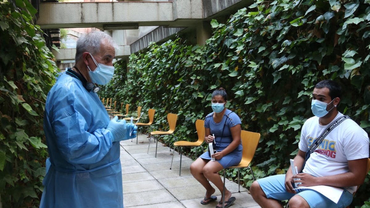 Un home indicant a diversos monitors com fer-se un test d'antígens.