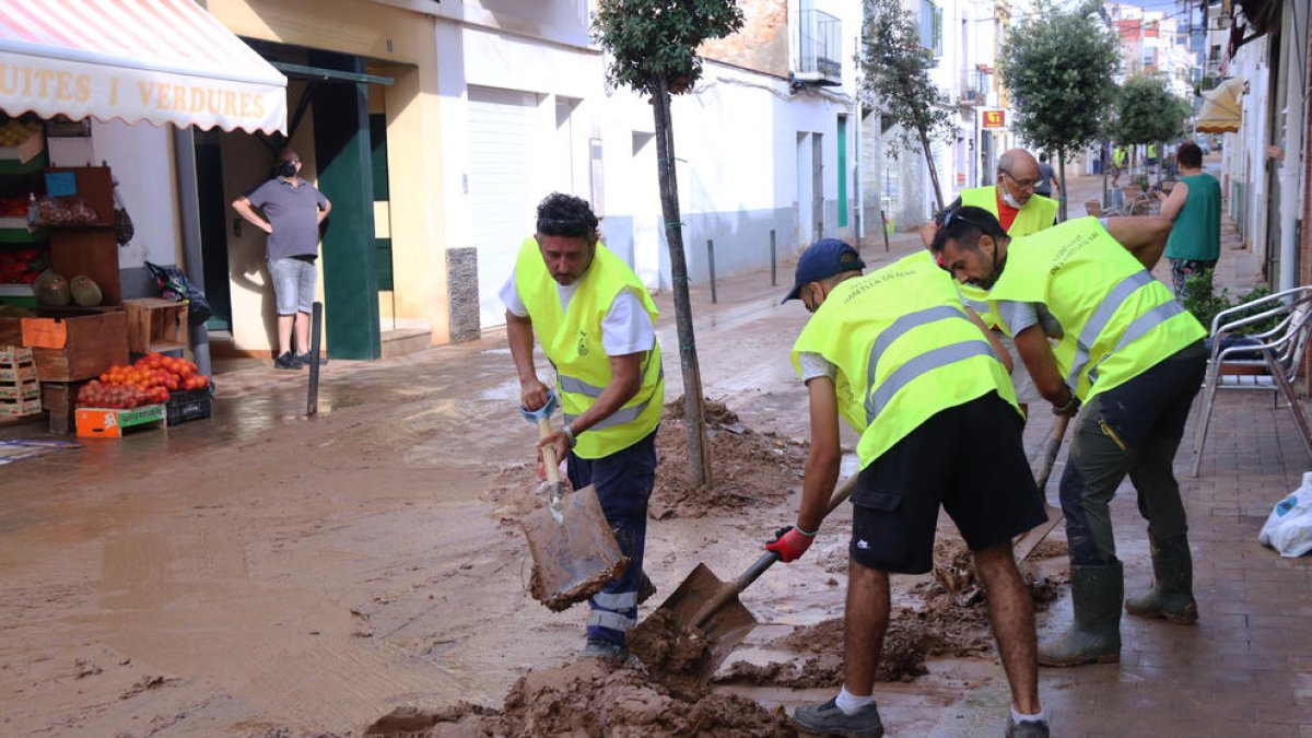 Un grupo de voluntarios de l'Ametlla de Mar trabajando en las tareas de limpieza de uno de las calles principales de las Cases d'Alcanar.